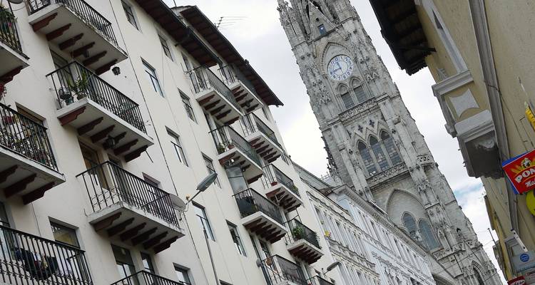 Historic clock tower viewed from a street with old buildings.