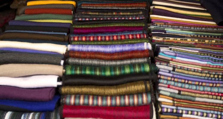 Stacks of colorful woven fabrics in various patterns.
