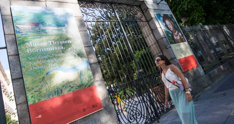 Le visiteur lit les affiches d'exposition à l'extérieur de la grille en fer forgé du Museo Thyssen-Bornemisza