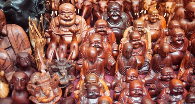 Colección de figurillas budistas e hindúes talladas en madera en exhibición en un puesto de mercado
