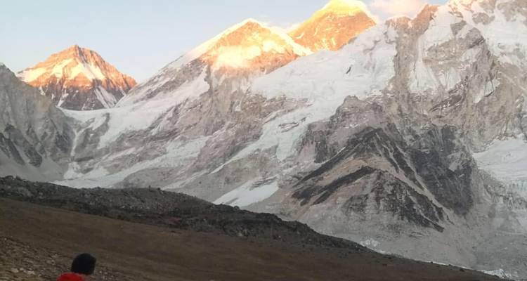 Sunrise light hits the summits of Everest, Lhotse and Nuptse above a rocky glacial valley.