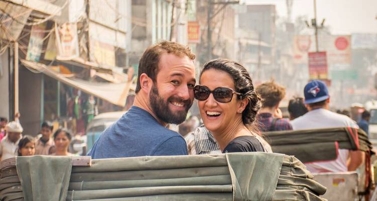 Pareja sonriendo mientras está sentada en un mercado lleno de gente.