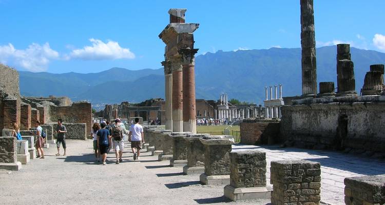 Turistas caminando por antiguas ruinas con vistas panorámicas de las montañas