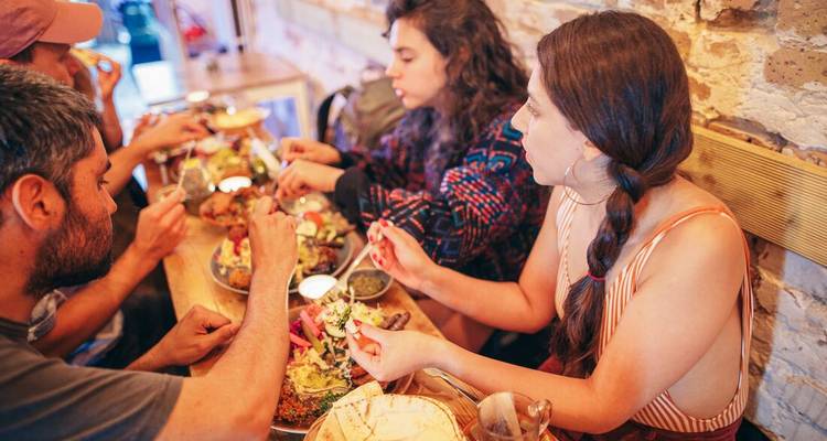 Des gens savourant un repas partagé dans un environnement chaleureux et rustique.