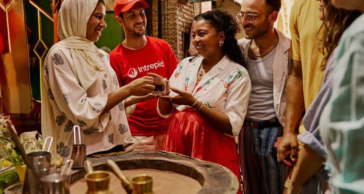Grupo de personas en un mercado marroquí compartiendo y disfrutando bebidas tradicionales.