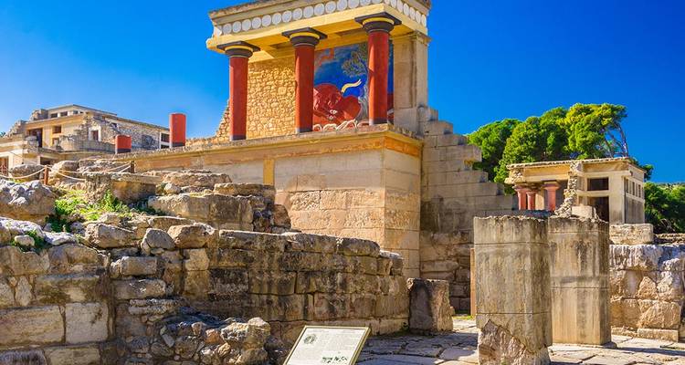 Farbenfrohe freskierte Säulen inmitten der antiken Palasttrümmer von Knossos unter lebhaft blauem Himmel