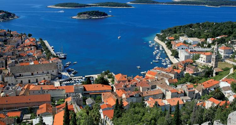 Malerischer Blick über eine Küstenstadt mit roten Dächern und blauem Meer.