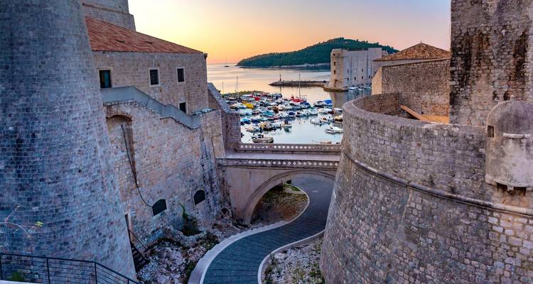 Vue du coucher de soleil sur les remparts médiévaux et le port de Dubrovnik.