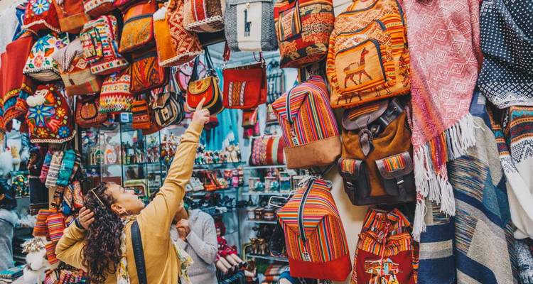 Market stall with colorful woven goods and shoppers.