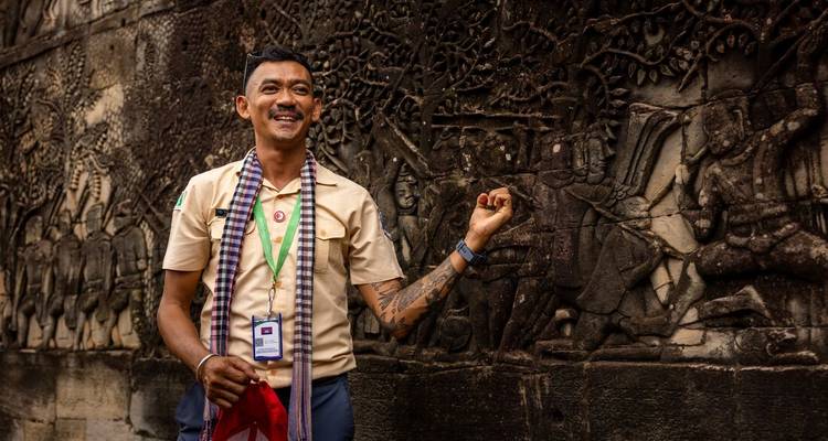 Smiling Cambodian guide explaining bas-relief carvings at Angkor Wat temple wall