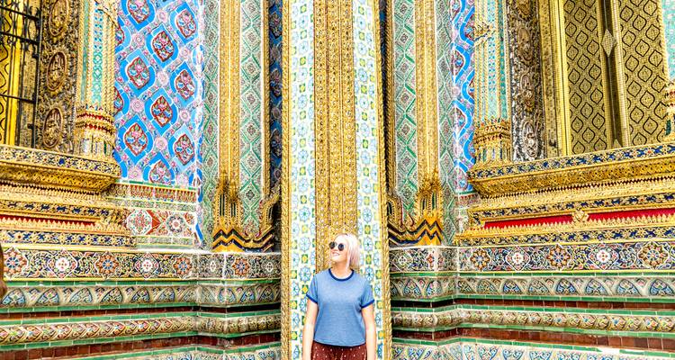 Traveler standing in front of an ornately decorated Thai temple facade covered in colorful mosaics and intricate patterns