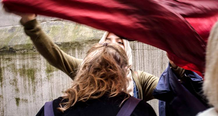Un moment spontané montrant quelqu'un qui soulève un tissu rouge tandis que des compagnons se tiennent à proximité dans une ruelle étroite.