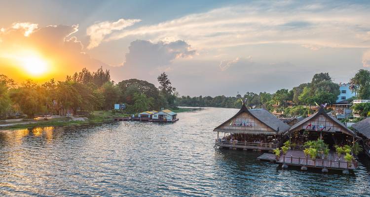 Puesta de sol sobre el río Kwai con casas flotantes de bambú y orillas del río exuberantes cerca de Kanchanaburi.