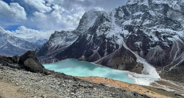 Turquoise gletsjermeer omgeven door steile, sneeuwbedekte Himalaya-wanden onder een dramatische hemel.