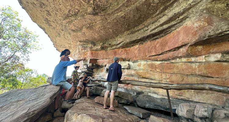 Des gens observant de l'art rupestre sur une paroi rocheuse.