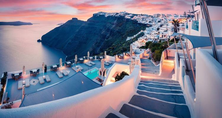 Les maisons à flanc de falaise de Santorin sous un ciel de coucher de soleil.