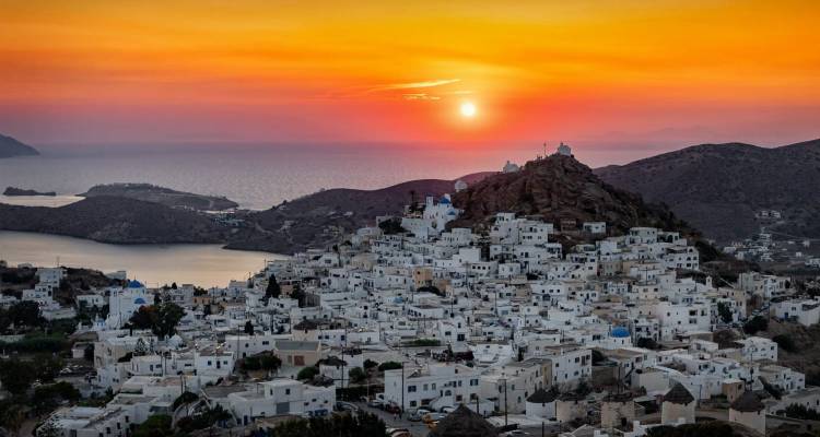 Coucher de soleil orange sur le village de montagne aux murs blanchis à la chaux de Chora sur l'île d'Ios.