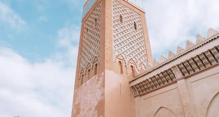 Dekoratives Minarett aus Ziegeln und Kacheln vor einem sanften bewölkten Himmel.
