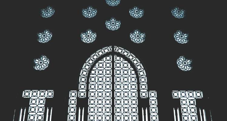 Aufwendiges geometrisches Buntglas- und Fliesenbogenmuster im Inneren einer großartigen Moschee.