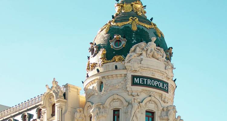 Die kunstvoll verzierte Kuppel des Metropolis-Gebäudes, umrahmt vom klaren blauen Himmel von Madrid.