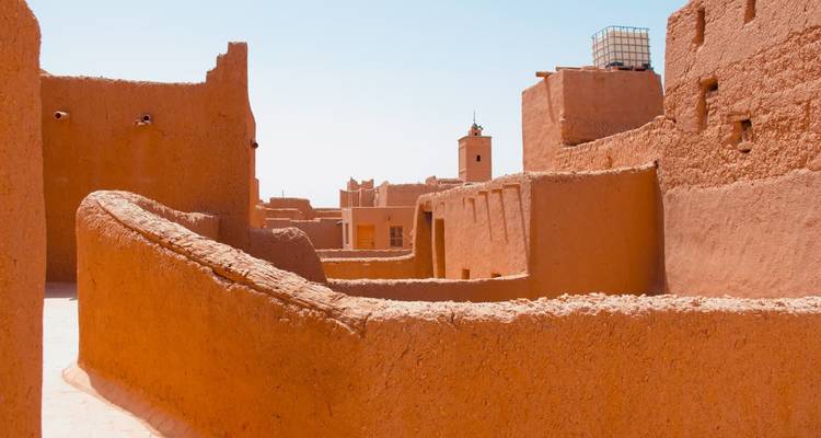 Des ruelles étroites et ensoleillées entre les hauts murs en terre d'une kasbah marocaine traditionnelle.