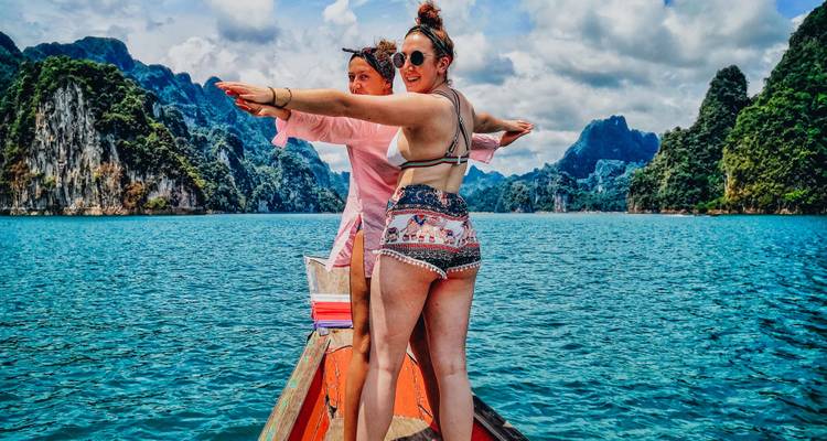 Deux femmes sur un bateau profitant d'un lac entouré de montagnes.