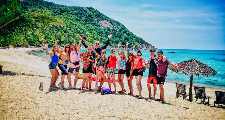 Groupe de touristes posant sur une plage avec un arrière-plan pittoresque.
