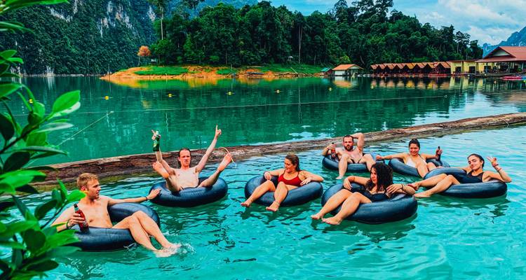 Des gens flottant dans des bouées sur un lac entouré de montagnes.