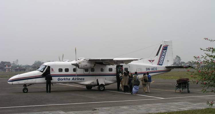 Pequeño avión de hélice aparcado en una pista con niebla.