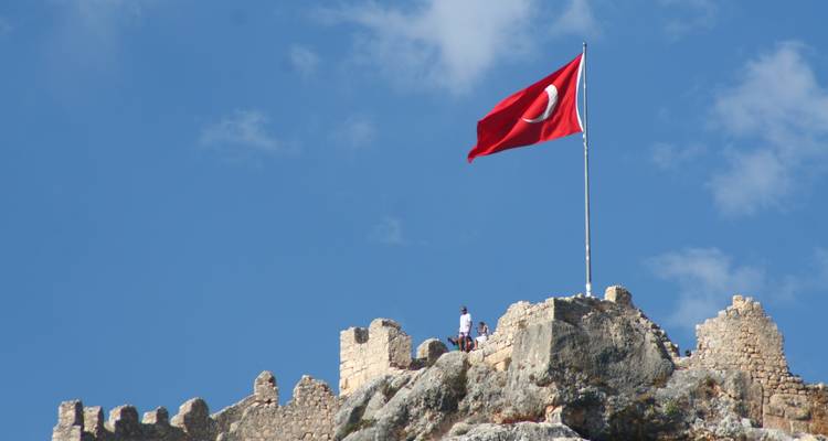 Bandera turca ondeando sobre ruinas de piedra históricas.