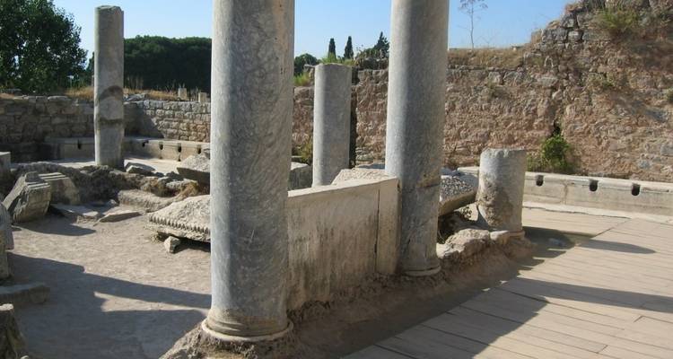 Ruinas antiguas con columnas en pie y piedras dispersas.