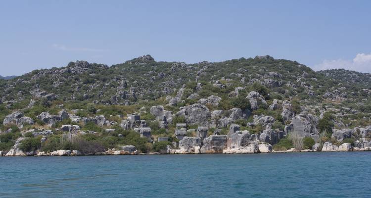 Paysage avec collines rocheuses et ciel dégagé surplombant la mer.