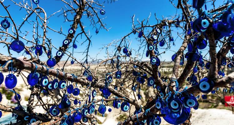 Arbre décoré de porte-bonheur œil bleu contre un ciel dégagé.