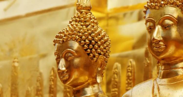 Nahaufnahme von zwei goldenen Buddhastatuen mit aufwendigen Details und warmen Reflexionen.