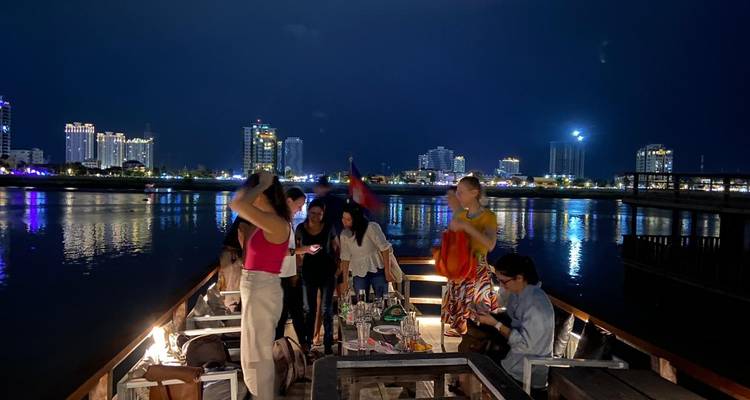 Gruppe von Menschen auf einem Boot in der Nacht mit Stadtlichtern.