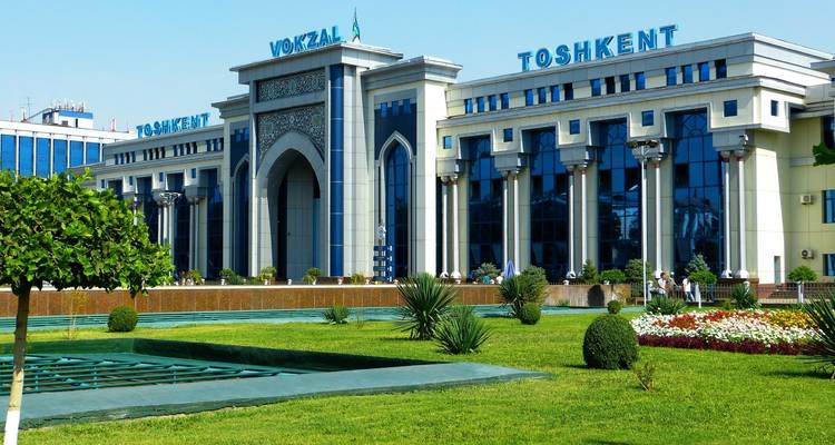 Edificio de estación de tren con un letrero que dice 'Toshkent Vokzal'.