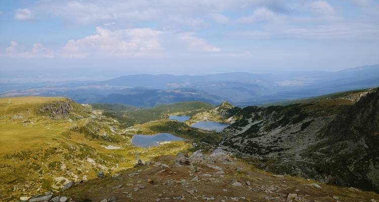 Paysage de montagne avec lacs et ciel nuageux.