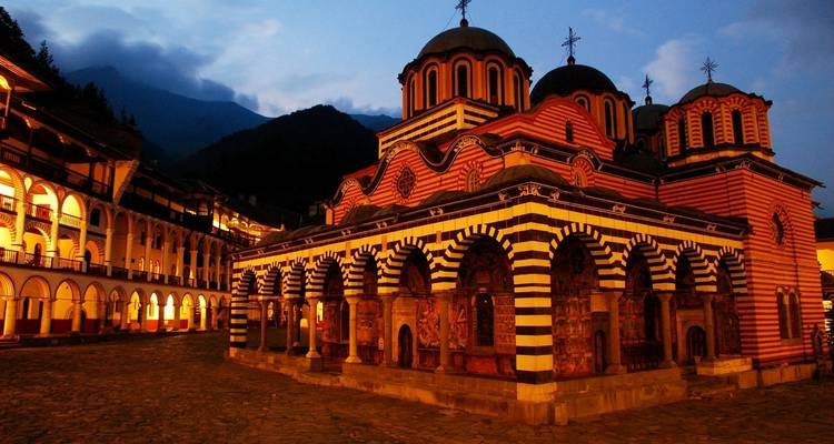 Monastère de Rila au crépuscule avec un éclairage dramatique.