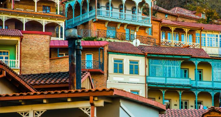 Colourful wooden-balconied houses stacked on a hillside in Georgia’s capital.