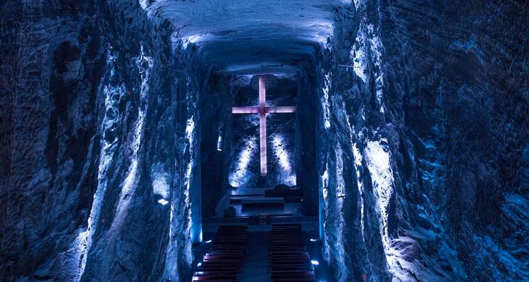 Illuminated cross inside the dramatic blue-lit cavern of the Salt Cathedral.