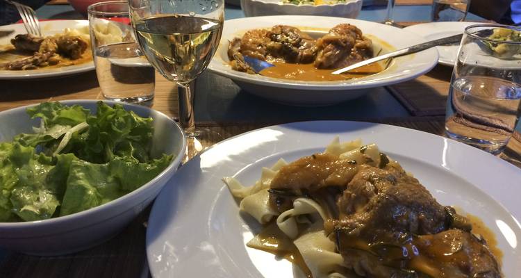 Home-style dinner table with pasta, salad and white wine ready to be enjoyed.