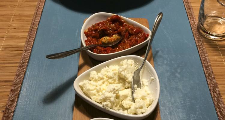 Two heart-shaped bowls hold creamy cheese and a red roasted-pepper relish on a placemat.