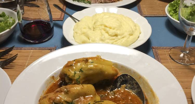 Poivrons farcis dans une sauce riche servis avec une purée de pommes de terre sur une table de dîner.