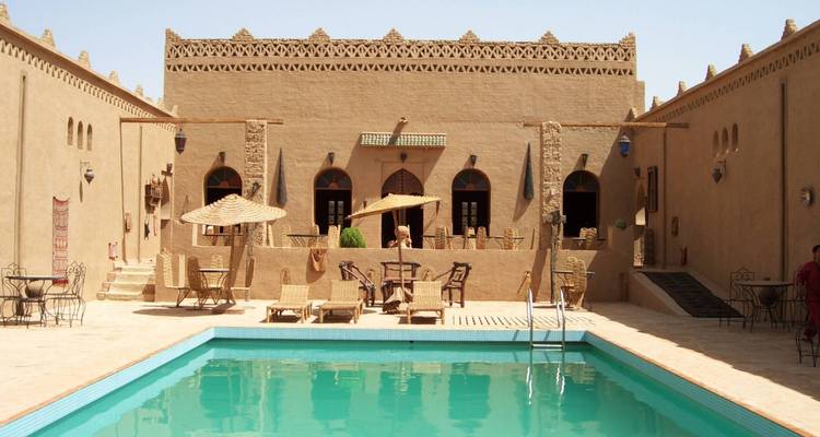Traditional desert guesthouse with an inviting swimming pool and sun umbrellas set in an adobe courtyard.