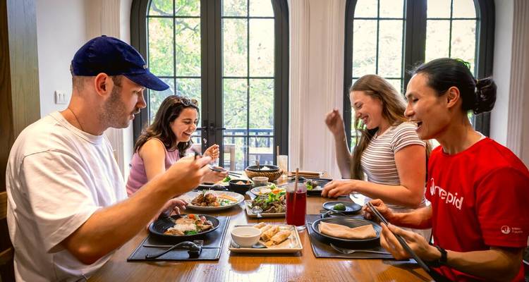 Les amis partagent des plats vietnamiens autour d'une table lumineuse aux grandes fenêtres