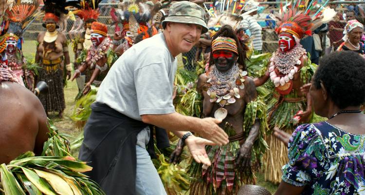 Un hombre interactuando con una persona con atuendo tradicional en un animado ambiente cultural.
