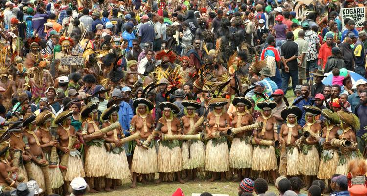 Una gran reunión con gente vestida con trajes tradicionales, algunos tocando instrumentos tradicionales.