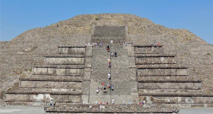 Visitors climb the wide central staircase of the Pyramid of the Sun under a clear blue sky at Teotihuacan.