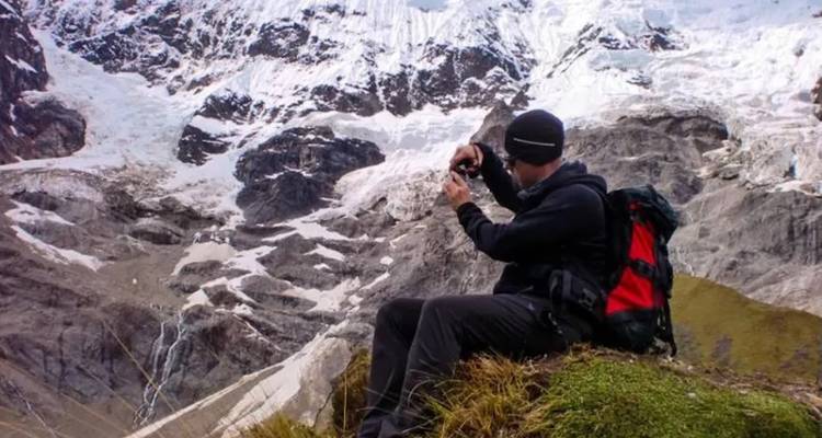 Persona fotografiando montañas con nieve y glaciares.