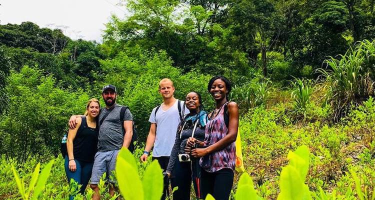 Un grupo de personas posando en un área con césped con árboles en el fondo.